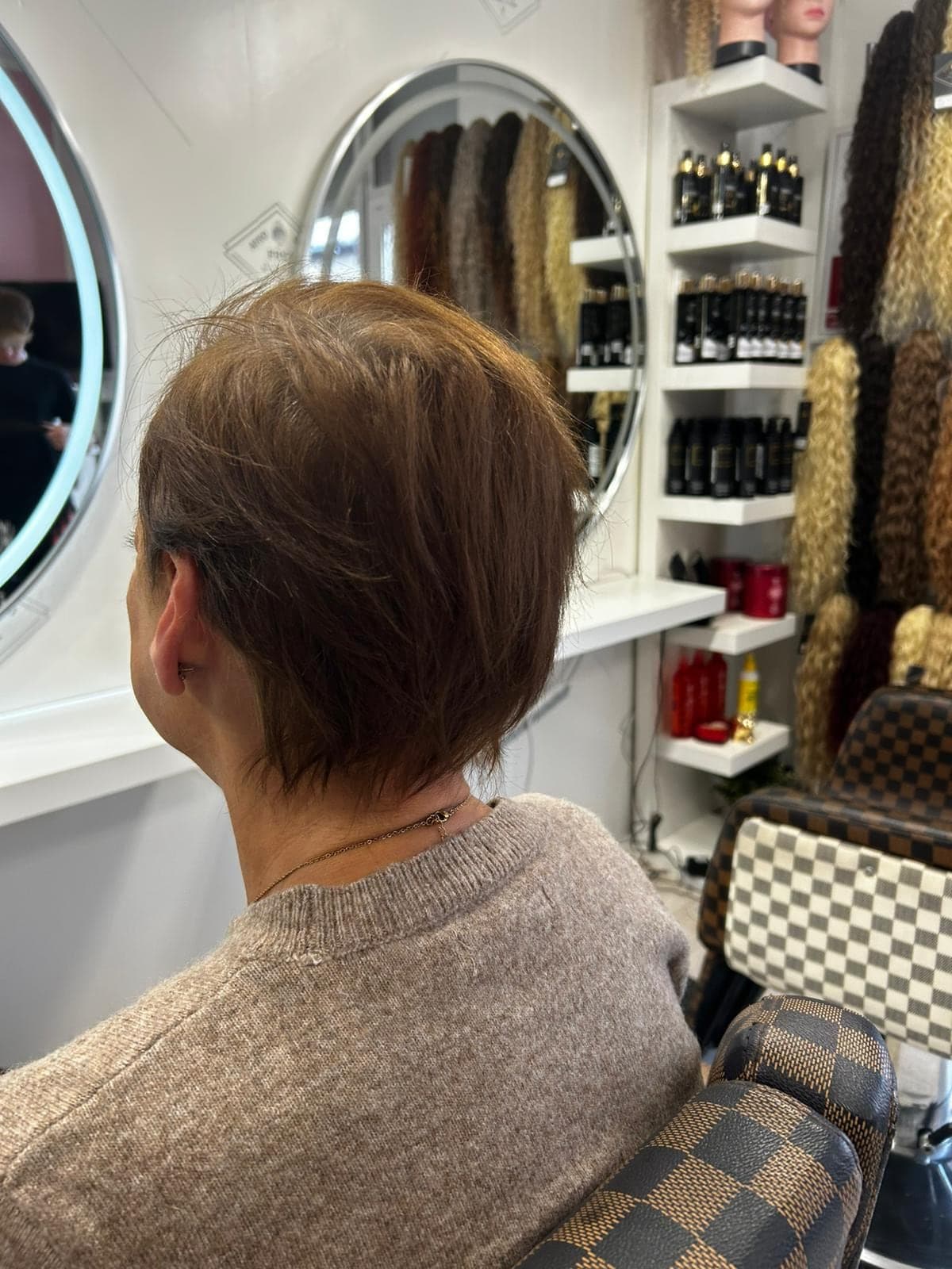 Wnętrze salonu FRYZ LOOK: lustra, półki z kosmetykami i pasma włosów syntetycznych